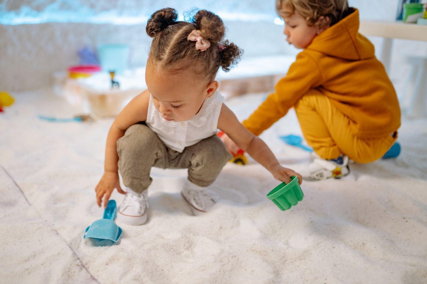Toddlers playing with sand and small buckets
